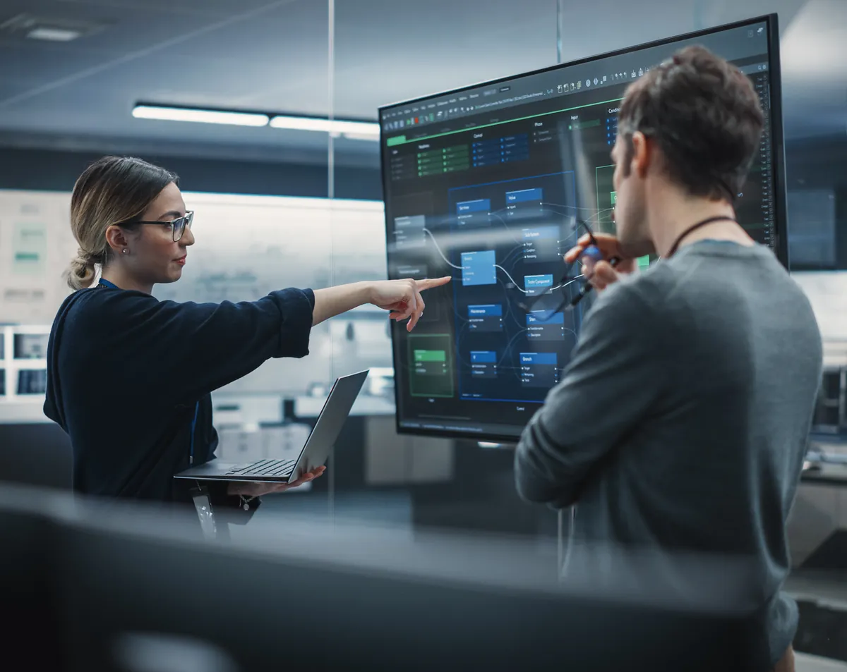 Two Numerico colleagues reviewing live operational dashboards on a large wall display